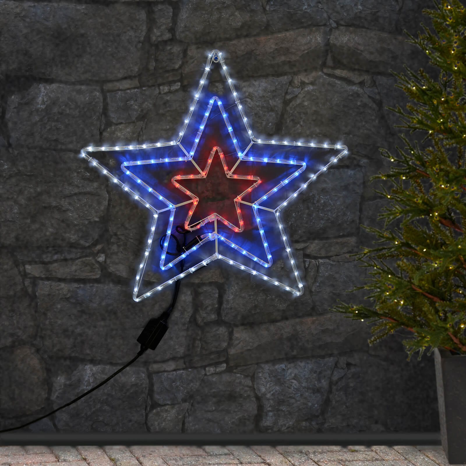 large triple star outdoor rope light silhouette with white, blue and red LED lights on a patio wall with Christmas tree in pot